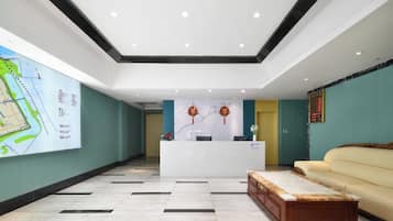 Um saguão de hotel com uma mesa de recepção, um mapa na parede, um sofá e um banco de madeira.
