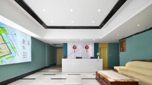 A hotel lobby with a reception desk, a map on the wall, a sofa, and a coffee table. - Ruining Hotel ( Xiangyang Gucheng North Street Branch) (Xiangyang)