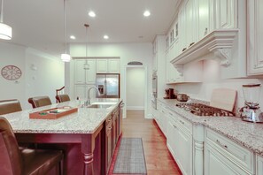A kitchen with white cabinetry, a granite countertop, and stainless steel appliances.