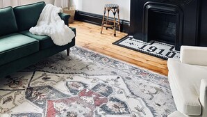 Una sala de estar con un sofá verde, un espejo grande, una chimenea y un candelabro.