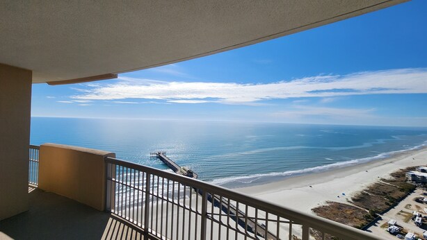 A balcony with a view of the ocean and a pier extending into the water. - SkyHigh Ocean Front Margate Tower (Myrtle Beach)