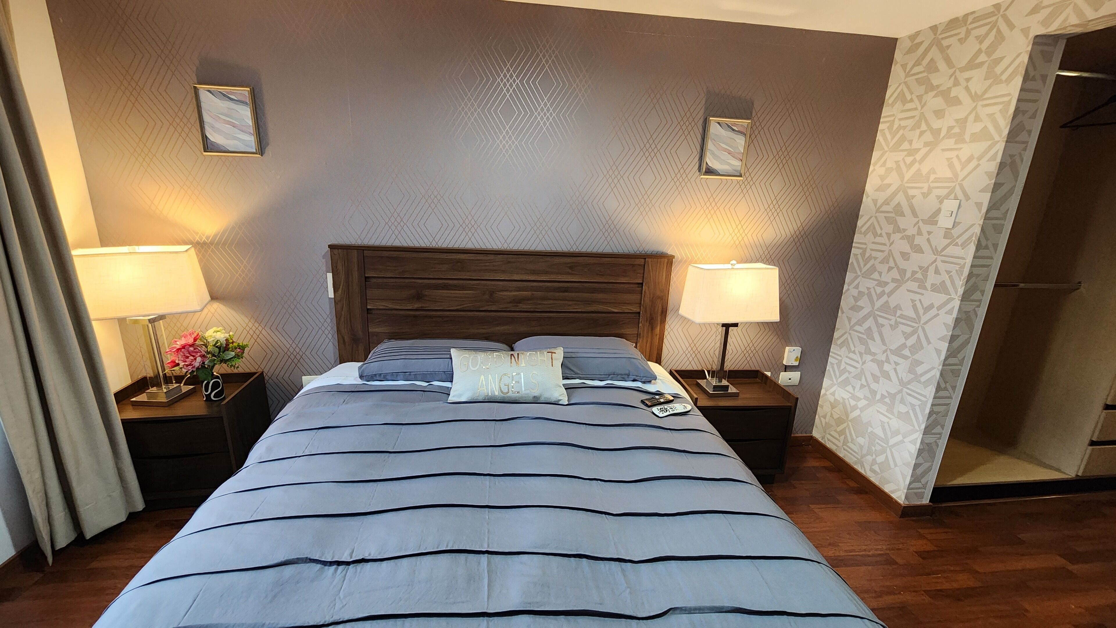 Camera d'albergo con un letto grande, due comodini con lampade e uno specchio sulla parete destra.