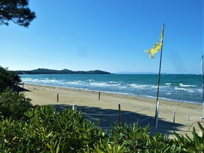 A beach with a flagpole and a clear view of the ocean.