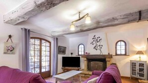 A living room with a fireplace, a television, and two purple sofas. - La Renardière by Interhome (Le Tignet)