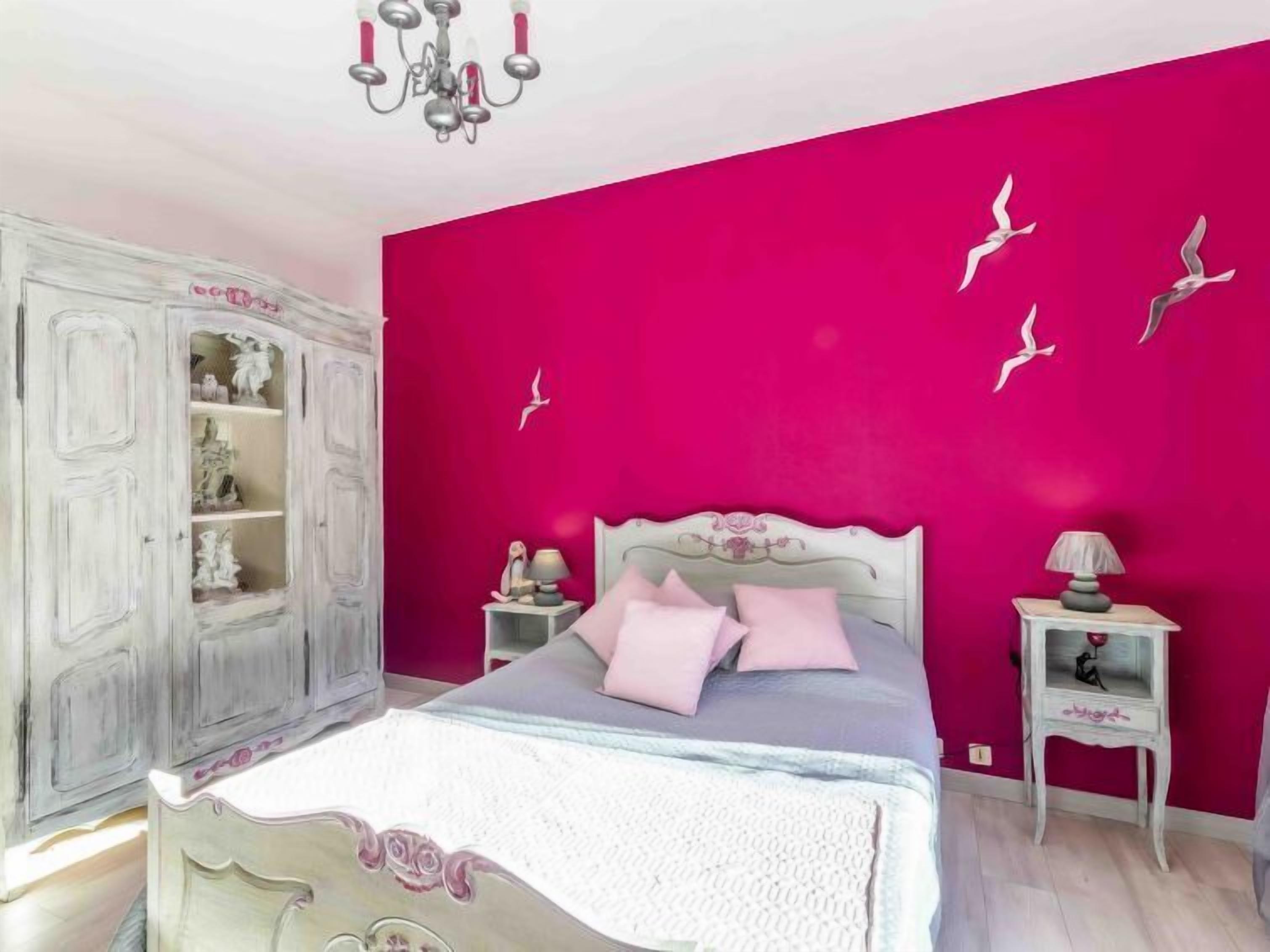 A bedroom with a bed, a nightstand, a dresser, and a chandelier.