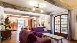 A spacious living room with a purple sofa, a wooden coffee table, and a large window with curtains. - La Renardière by Interhome (Le Tignet)