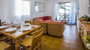 A dining area with a table set for four, a sofa, and a balcony with chairs. - Laguna Beach Plus by Interhome (Dénia)