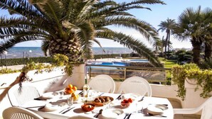 A table set for four with white chairs, a view of the sea, and a pool in the background. - Laguna Beach Plus by Interhome (Dénia)