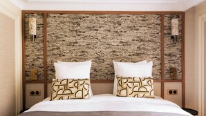 A hotel room with a large bed, two pillows with geometric patterns, a textured wall, and two wall-mounted lamps. - Merveil Luxury Suite - Louvre - Dalayrac (Paris)