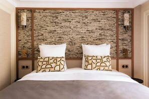 A hotel room with a large bed, two pillows with geometric patterns, a textured wall, and two wall-mounted lamps. - Merveil Luxury Suite - Louvre - Dalayrac (Paris)