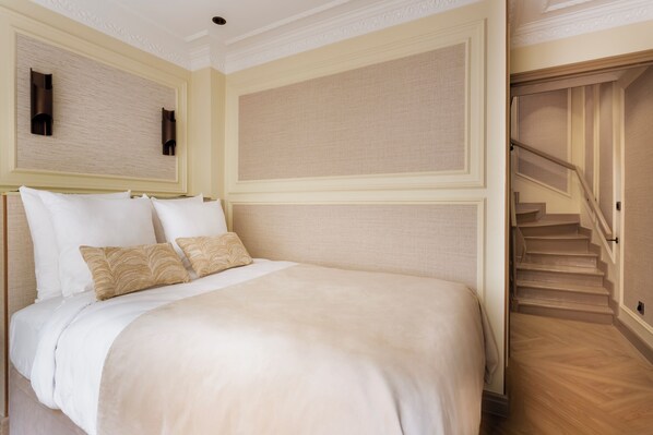 A hotel room with a bed, a staircase, and a textured wall. - Merveil Luxury Suite - Louvre - Dalayrac (Paris)