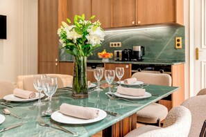 A dining table set with plates, cutlery, and glasses, with a vase of flowers in the center.