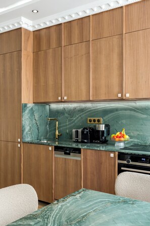 Una cocina moderna con armarios de madera, encimera de mármol y cafetera.