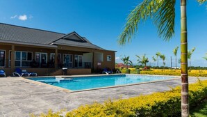 Un hôtel doté d’une piscine, de chaises longues et de palmiers.