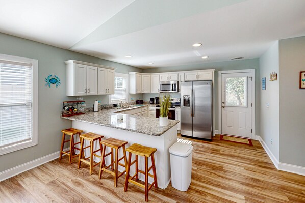 Enjoy cooking in this kitchen with a central island, bar stools, stainless steel appliances, and ample counter space.