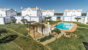 Un quartier résidentiel avec des maisons blanches, une piscine et une pergola.