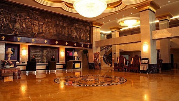 A spacious lobby with a grand chandelier, a large mural, and a central circular floor design. - Dele Grand Hotel (Xiangcheng)