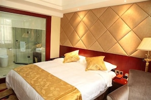 A hotel room with a large bed, a glass shower enclosure, a red headboard, and a bedside table with a lamp. - Dele Grand Hotel (Xiangcheng)