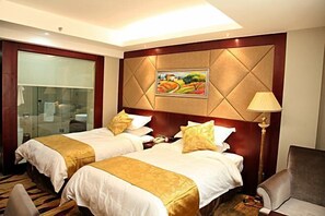 Een hotelkamer met twee bedden, een groot raam, een schilderij aan de muur en een lamp.