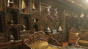 An ornate room with intricate wood carvings, a wooden sofa, and a glass table. - Dele Grand Hotel (Xiangcheng)