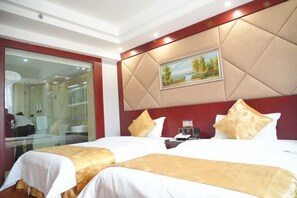 Een hotelkamer met twee bedden, een groot schilderij aan de muur en een glazen deur naar een badkamer.