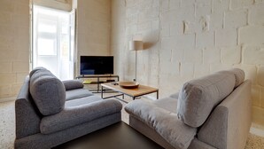A living room with two grey sofas, a flat-screen TV, a wooden coffee table, and a floor lamp.