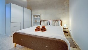A bedroom with a bed, a wardrobe, a bedside table, and a lamp.
