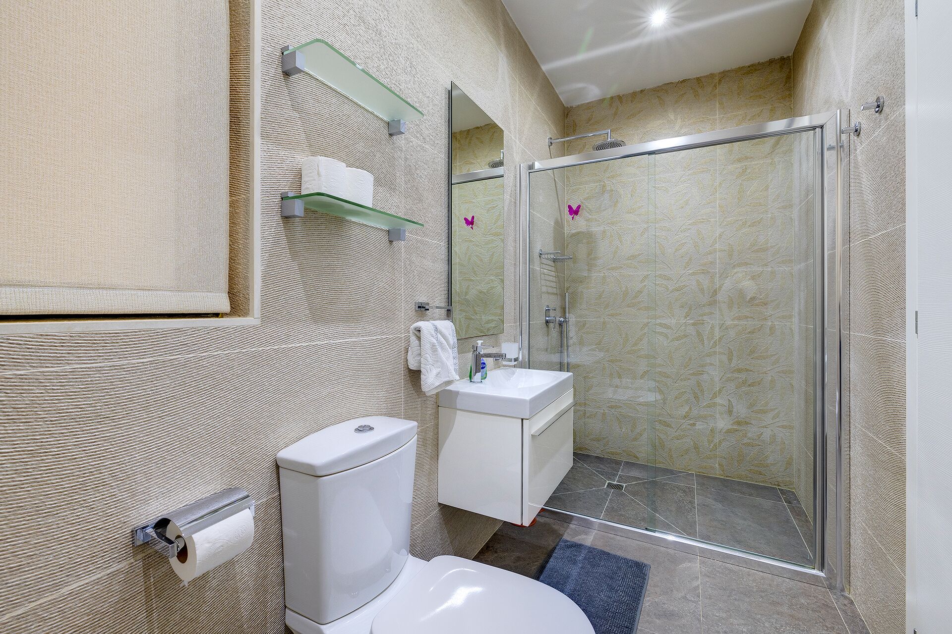 Een moderne badkamer met toilet, wastafel en douchecabine met glazen wanden.