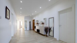 Un pasillo moderno con suelo de madera, paredes blancas y una puerta blanca al final.