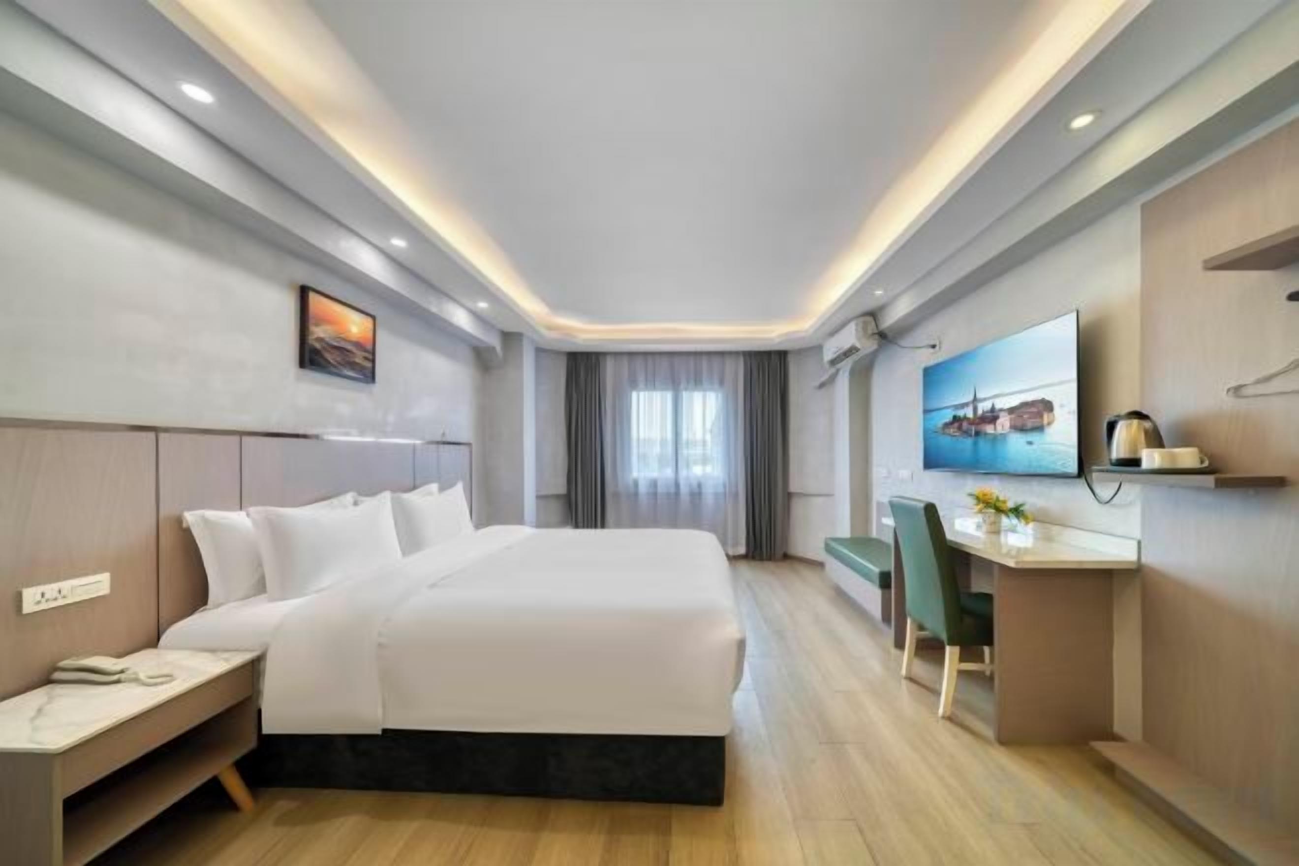 Ein Hotelzimmer mit Bett, Nachttisch, Schreibtisch, Stuhl und einem an der Wand befestigten Fernseher.