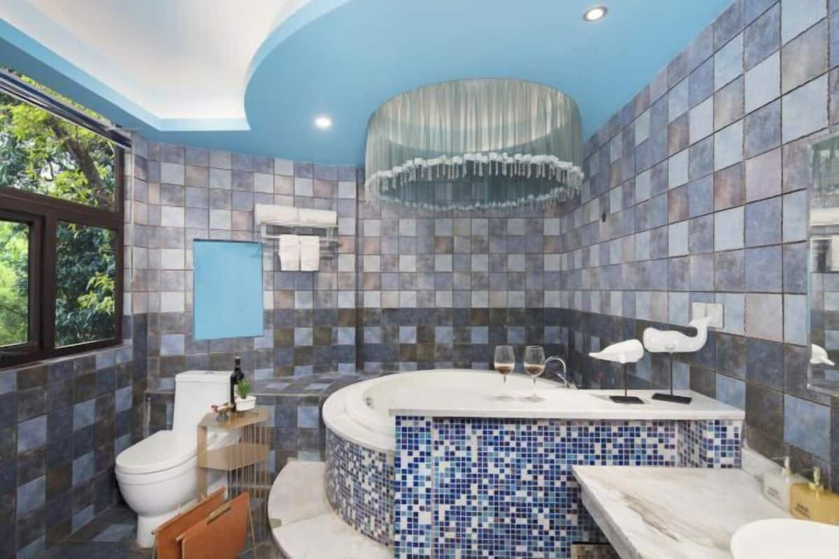 A modern bathroom with a mosaic tile wall, a freestanding bathtub, and a large mirror.
