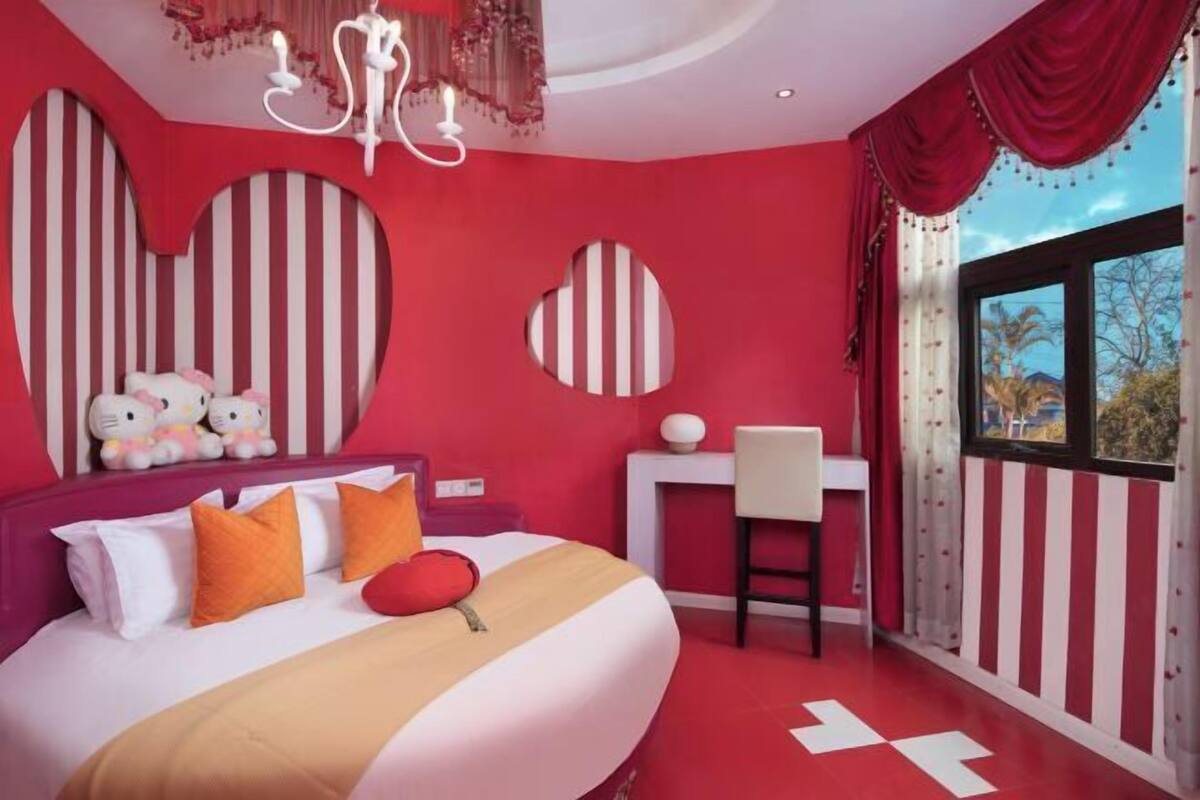 A bedroom with a bed, a desk, and a window with a view.