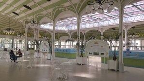 Amplio espacio interior con techos altos y estructuras arqueadas, con paneles de vidrio transparente y columnas blancas.
