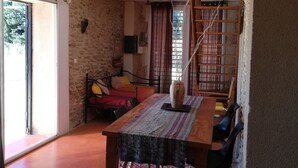 Una stanza con un tavolo da pranzo in legno, un divano rosso, un muro in pietra e una scala in legno.