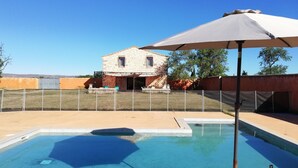 Una piscina con vista su una casa in pietra sullo sfondo.