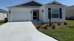 Une maison de plain-pied avec une porte de garage blanche, une entrée principale et un petit porche.