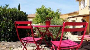 Un conjunto de mesa y sillas metálicas rojas al aire libre, con una planta en maceta sobre la mesa.