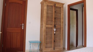 Una habitación con un armario de madera, una mesita pequeña y una cama.