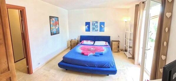 Un dormitorio con una cama grande, un armario y una puerta que da a otra habitación.