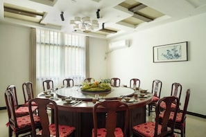 A dining room with a round table, red upholstered chairs, and a chandelier. - Yaoli Holiday Hotel (Fuliang)