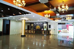 Un hall de hotel con mostrador de recepción, candelabros y fachada de vidrio.