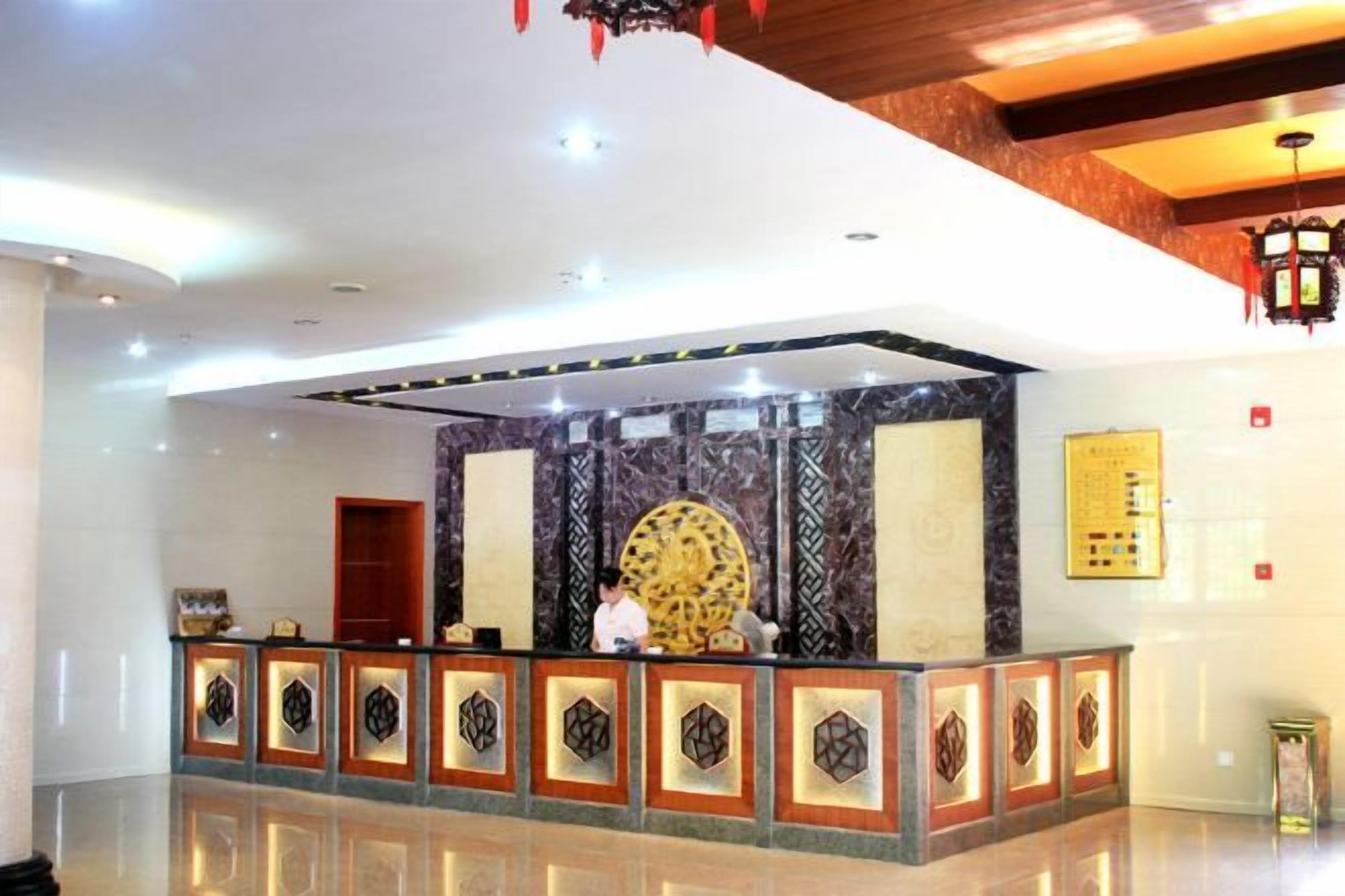 A reception area with a marble wall, a large circular decorative piece, and a reception desk with patterned borders.
