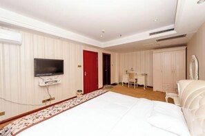 A hotel room with a bed, a television mounted on the wall, a desk, and a wardrobe. - Yaoli Holiday Hotel (Fuliang)