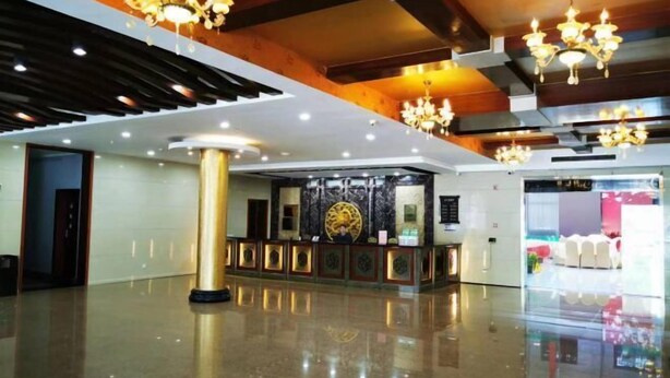 A spacious lobby with a reception desk, chandeliers, and a polished floor.