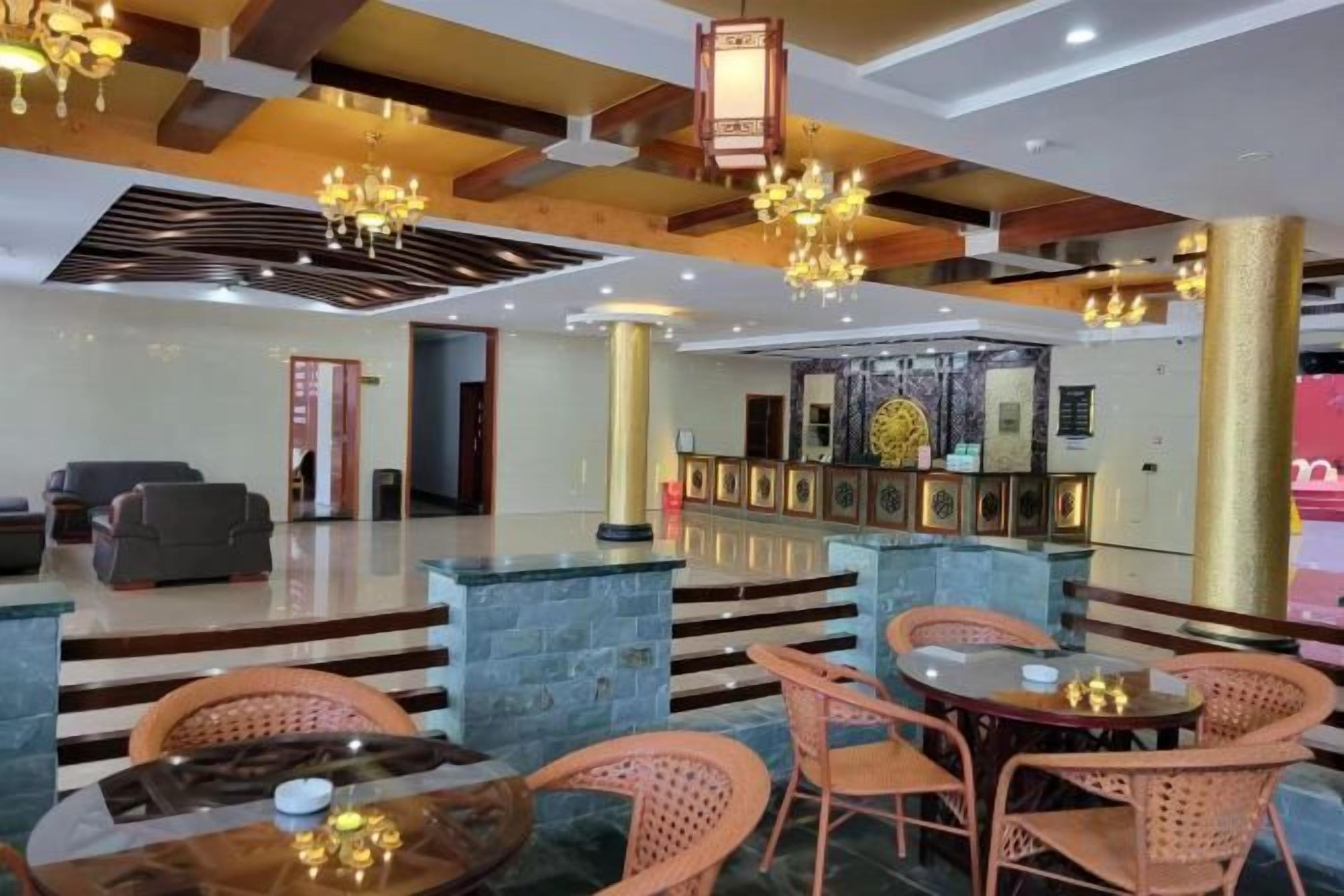 Een hotellobby met een receptiebalie, een zithoek en een trap naar de verdiepingen.