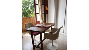 Comedor con una mesa preparada para dos personas, dos sillas y vistas a zonas verdes al exterior.