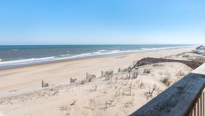 A beach with a wooden boardwalk and dunes. - Golden Strand Unit J2: Oceanfront | Shared Pool (Kill Devil Hills)