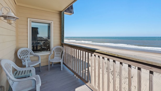 A wooden deck with a railing overlooking a beach. - Golden Strand Unit J2: Oceanfront | Shared Pool (Kill Devil Hills)