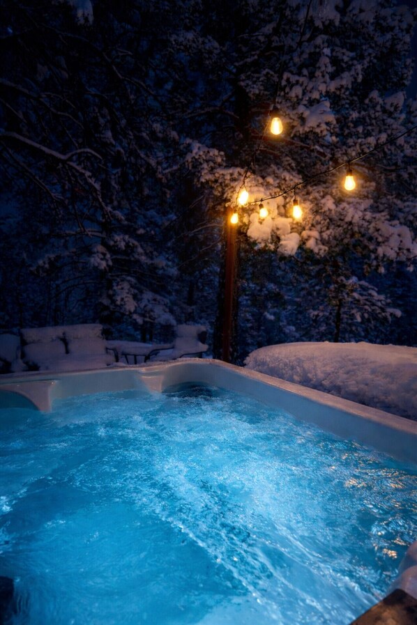 Una piscina climatizada al aire libre rodeada de árboles cubiertos de nieve.