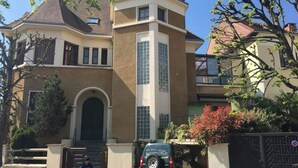 A two-story house with a prominent arched entrance, a garage, and a car parked in front. - F1 overlooking Lac d'Allier and park, 5' from thermal baths (Vichy)